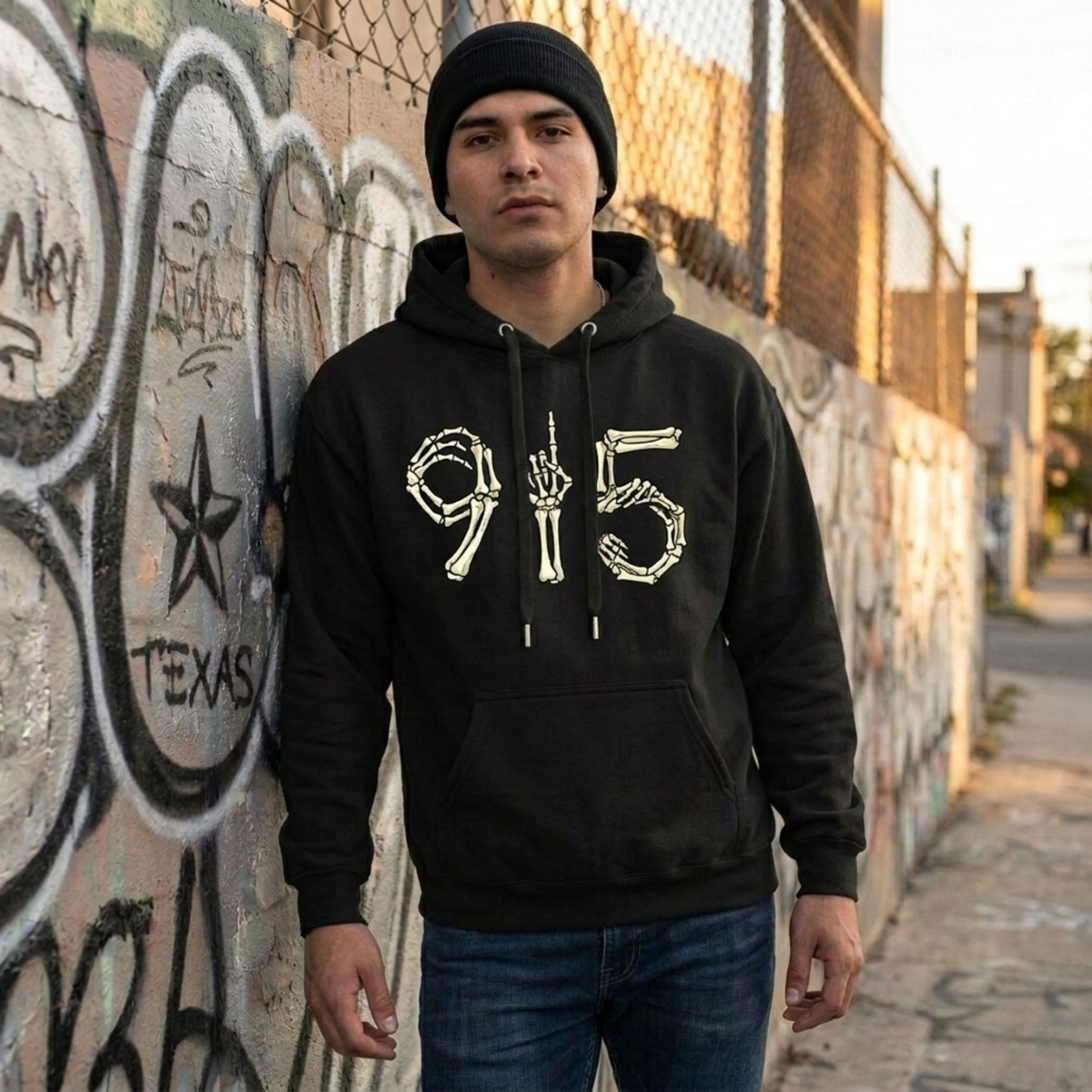 man wearing black hoodie graffiti wall behind