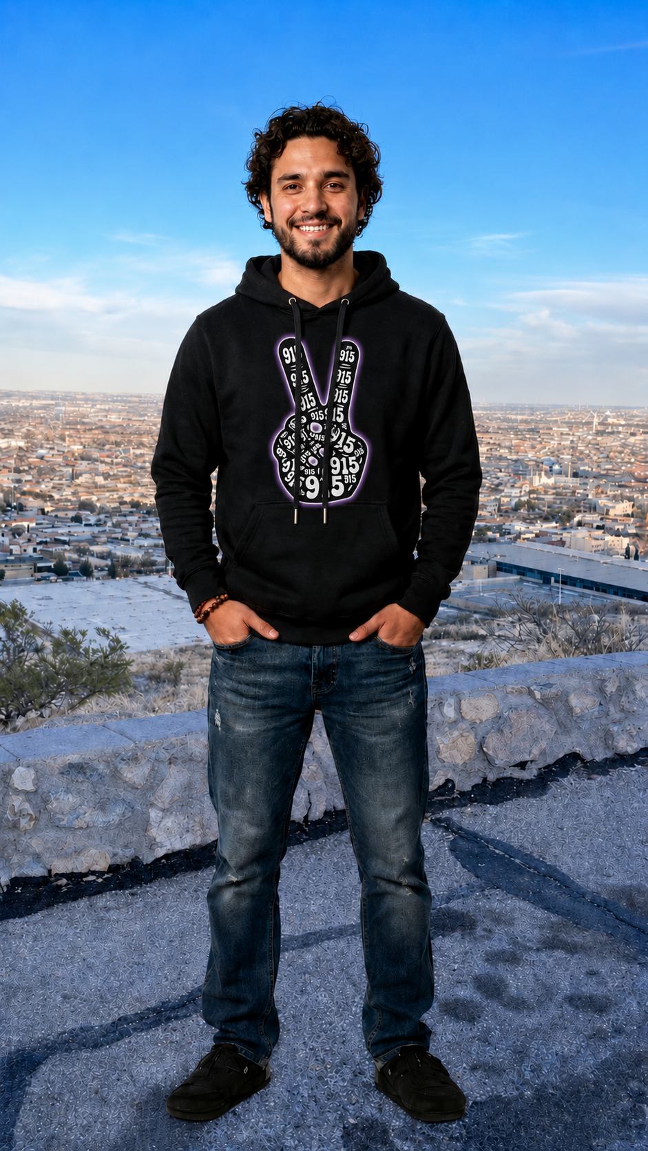 Person wearing a black hoodie with a white logo, standing on a high vantage point with a cityscape in the background.