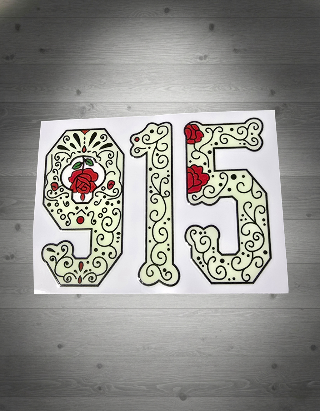 Decorative sticker with numbers '915' featuring floral designs on a wooden surface