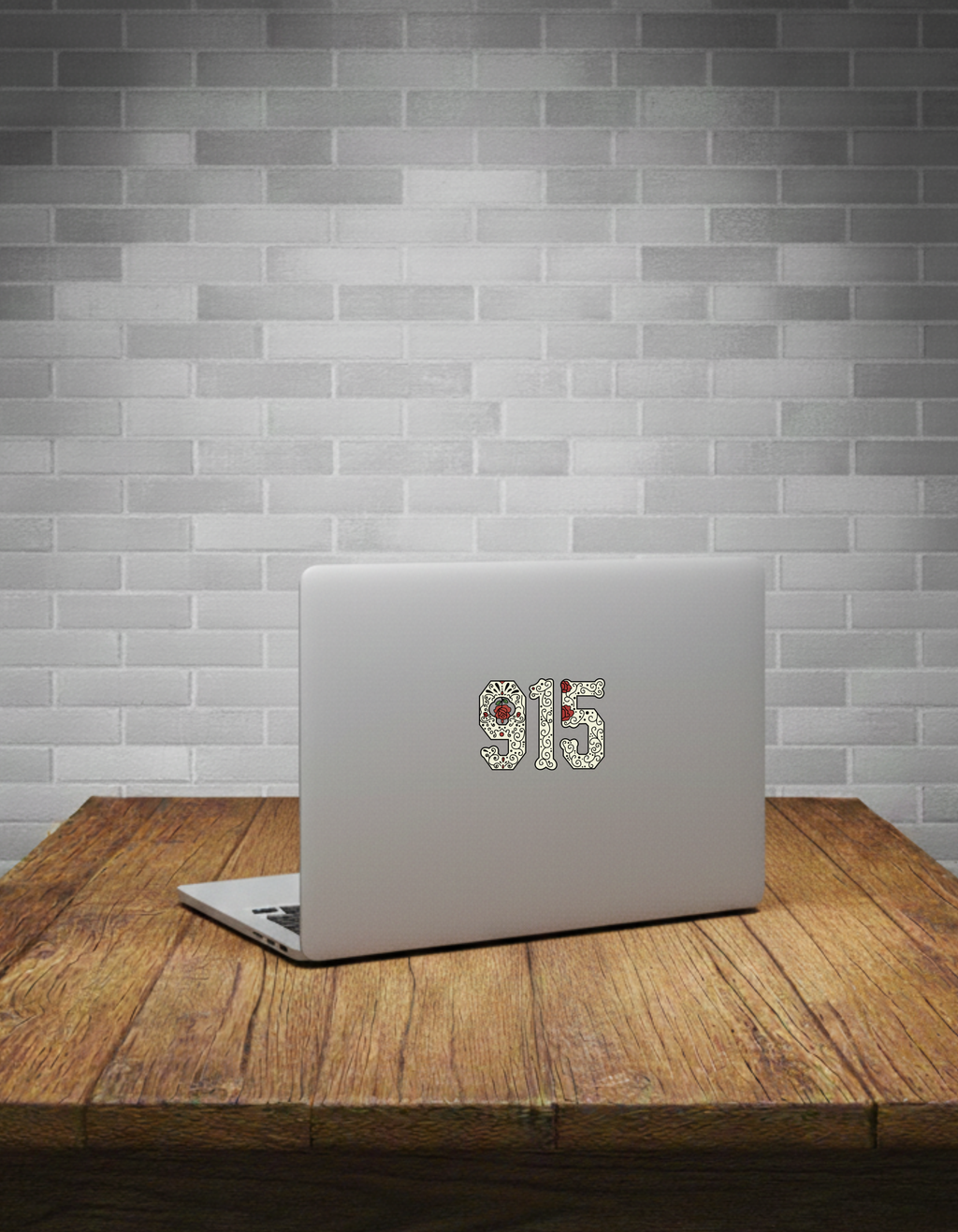 Laptop with '915' decal on a wooden table against a tiled wall.
