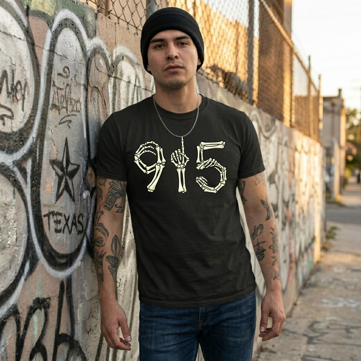 Man wearing a black t-shirt with a graphic design, standing against a graffiti-covered wall.