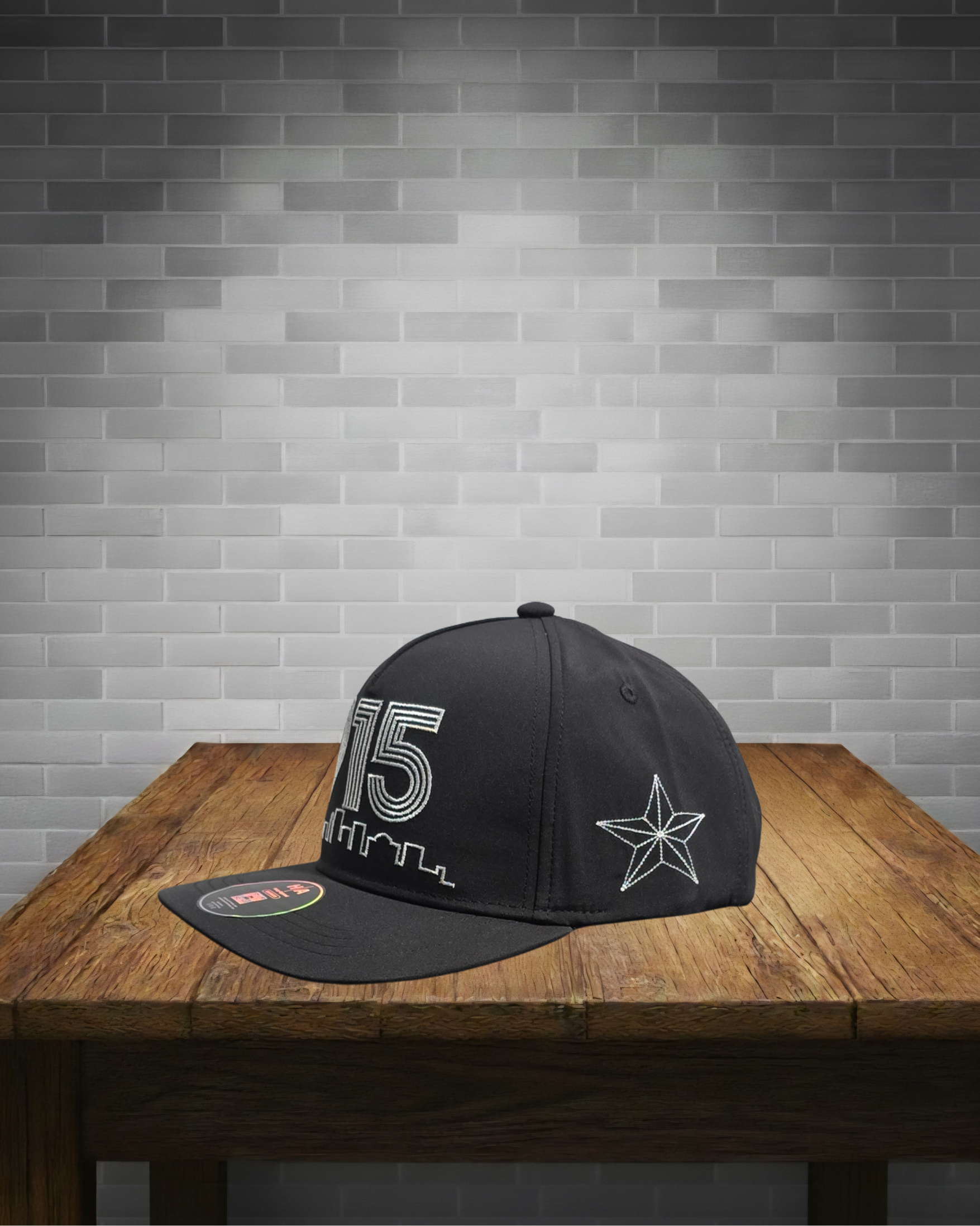 Black cap with white designs on a wooden table against a gray brick wall.