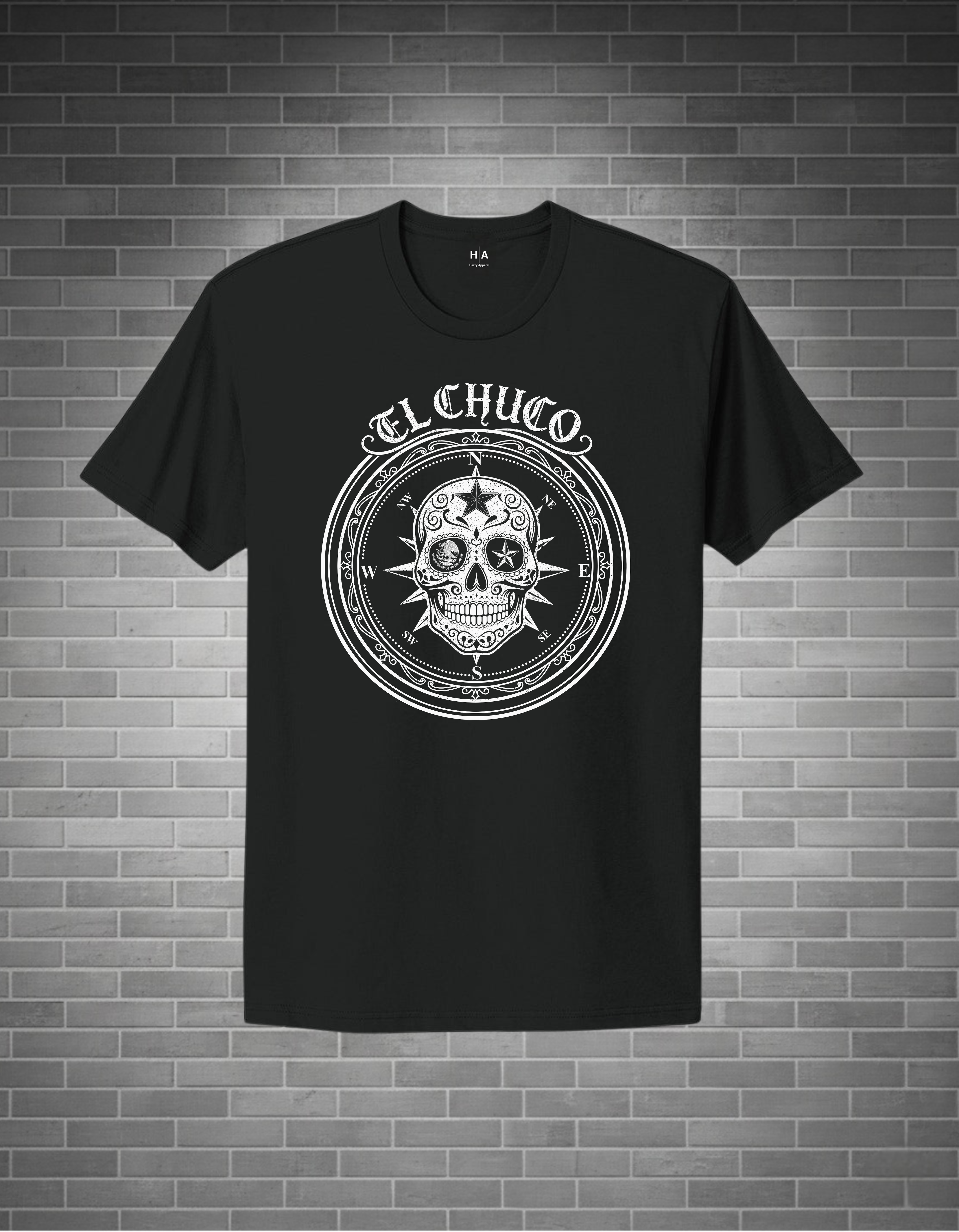 Black t-shirt with a white skull design and 'El Chuco' text on a brick wall background