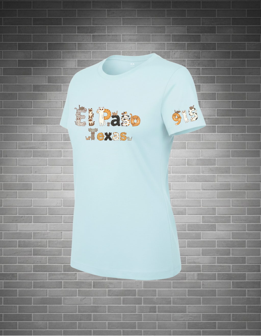 Light blue t-shirt with 'El Paso Texas' cat text design and 915 cat design on a brick wall background