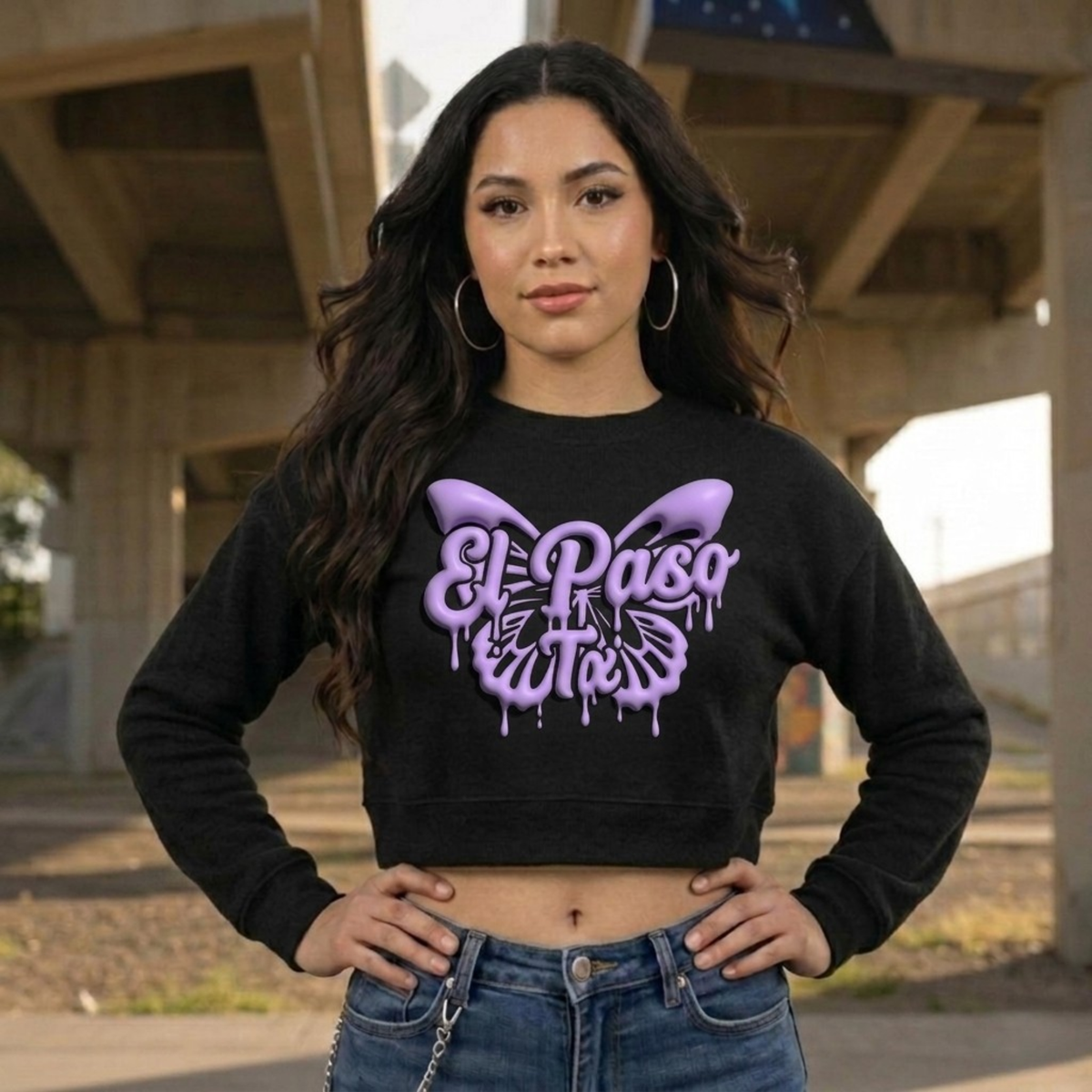 Woman wearing a black sweatshirt with a purple butterfly design and 'El Paso' text, standing outdoors.