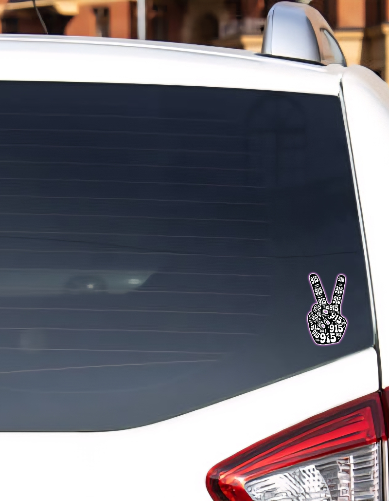 Car window with a peace sign decal on a blurred background