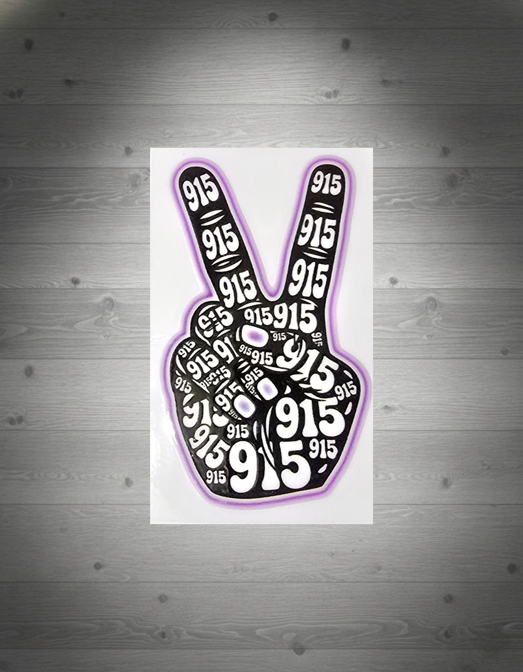 Peace sign with '915' printed multiple times on a white grey wooden background