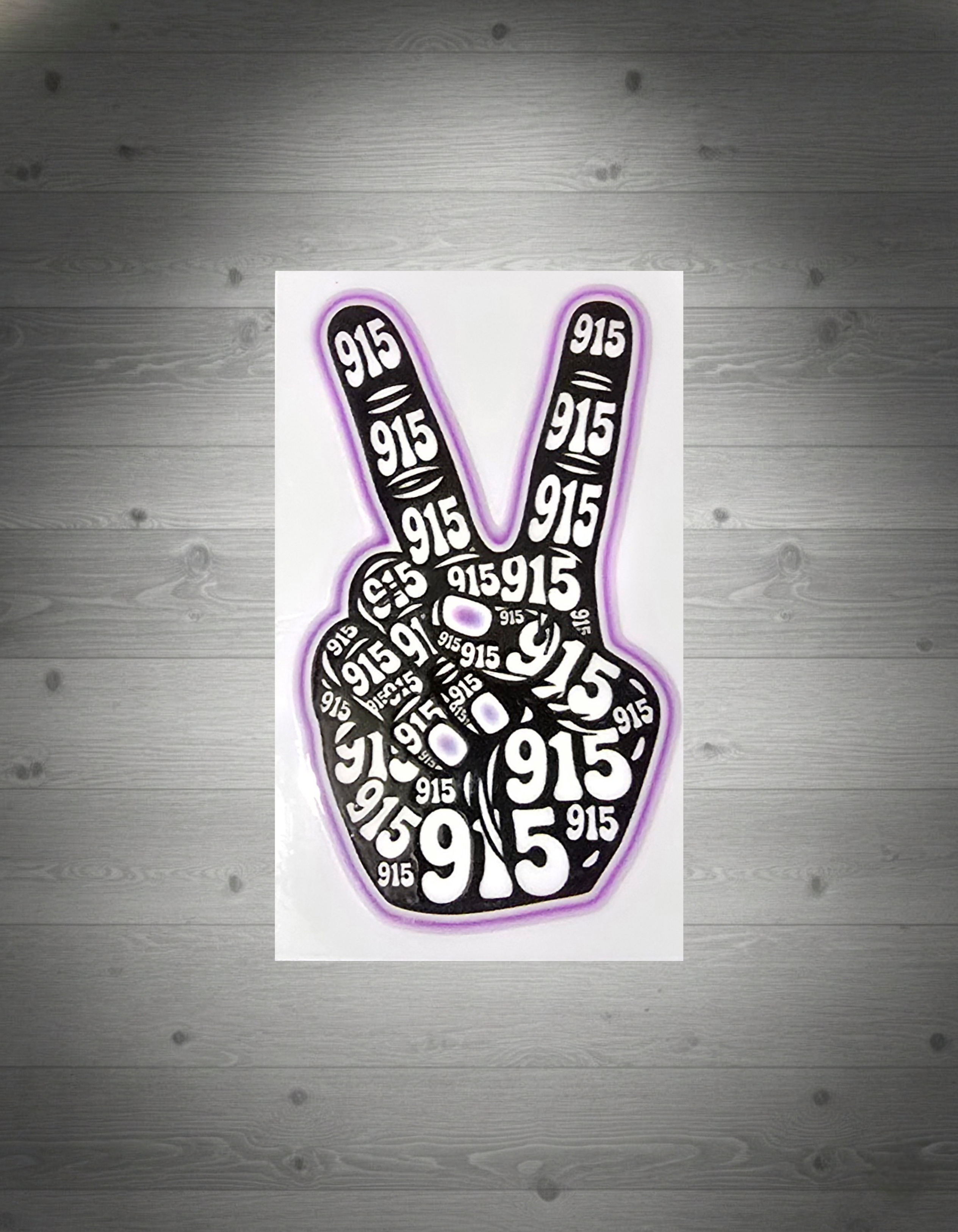 Peace sign with '915' printed multiple times on a white grey wooden background