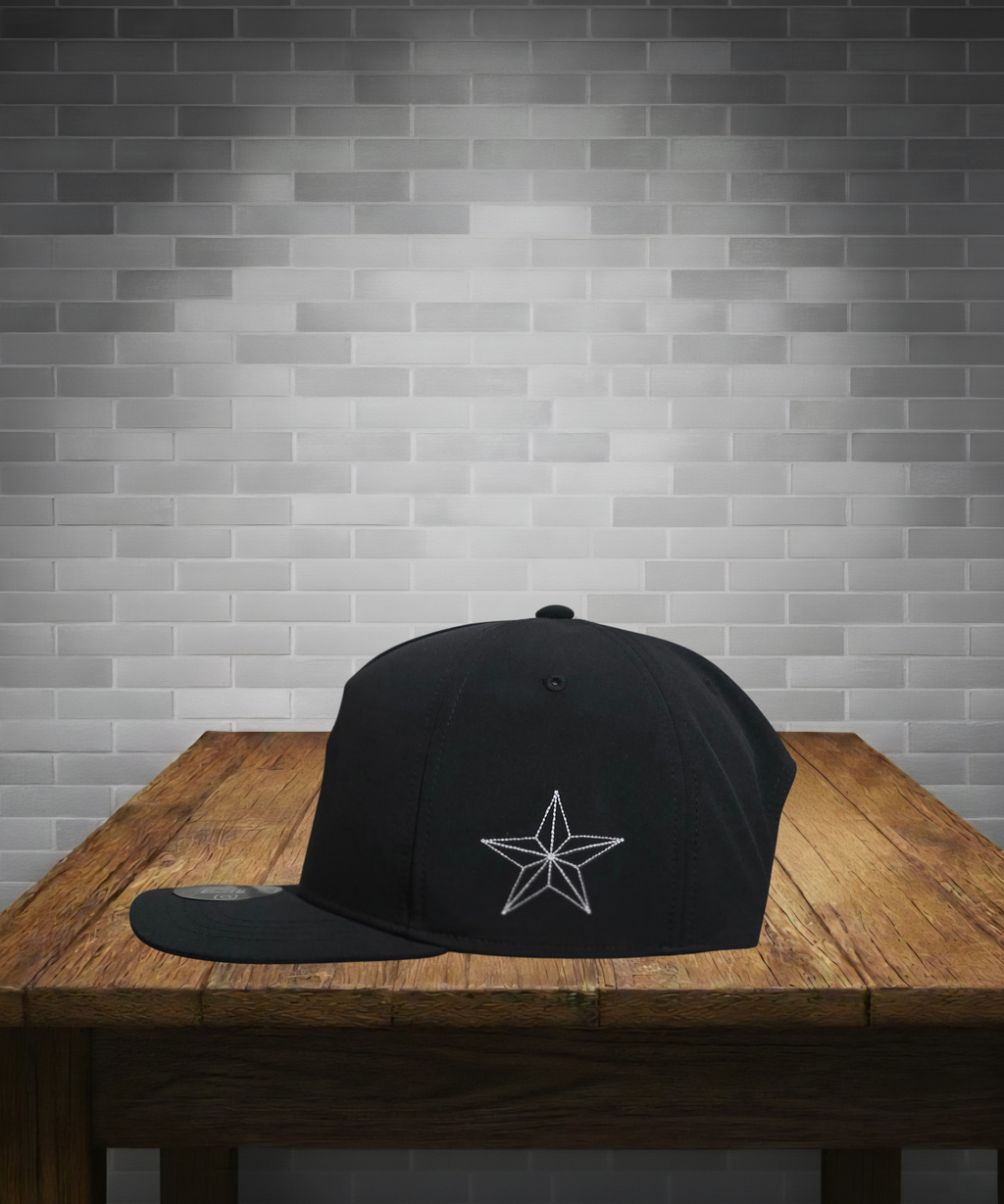 Black cap with a white star design on a wooden table against a gray brick wall.
