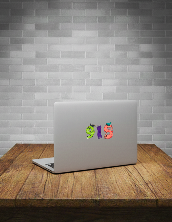 Laptop with colorful Cat sticker on a wooden table against a grey brick wall.