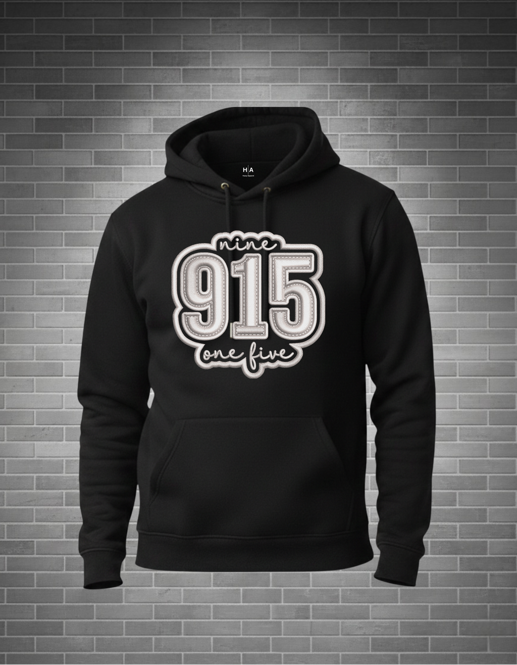 Black hoodie with '915 one five' in white text on a brick wall background