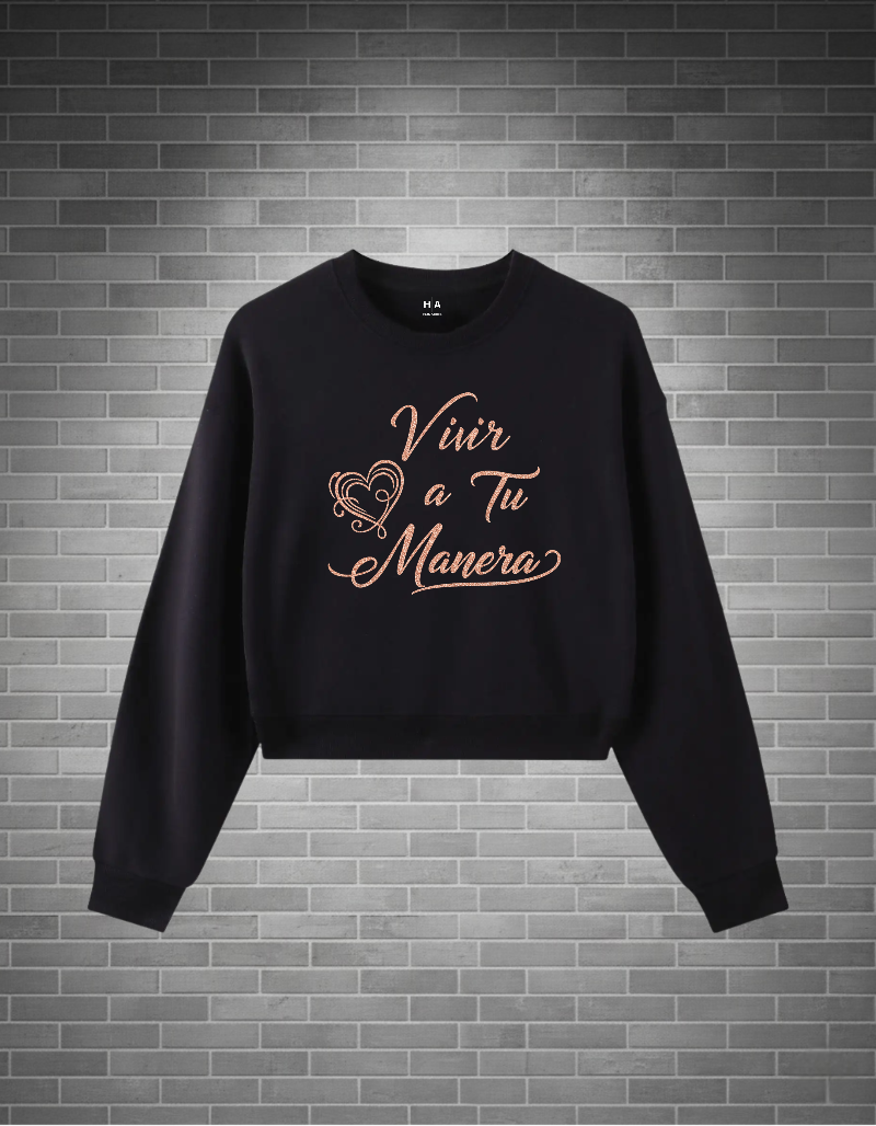 Black sweatshirt with 'Vivir a Tu Manera' (live your way) text on a brick wall background